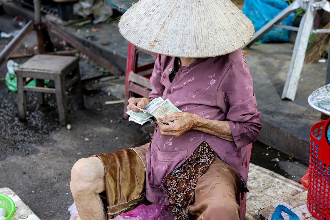 Old woman counting money, Hoi An, Vietnam (2k22)